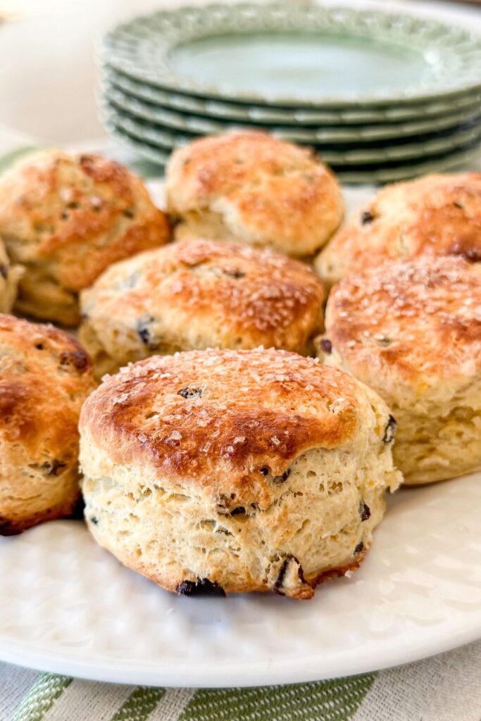 close up of flaky Irish soda bread scones with currants and sanding sugar on a white plate