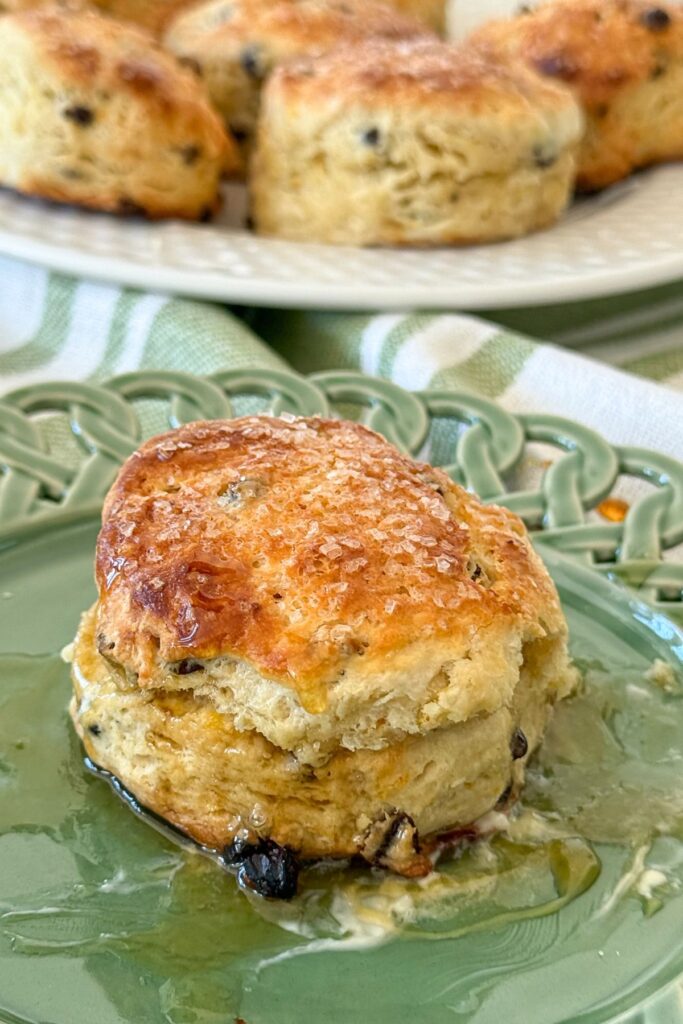 Irish soda bread scone with currants topped with sanding sugar and drizzled with honey on a green plate
