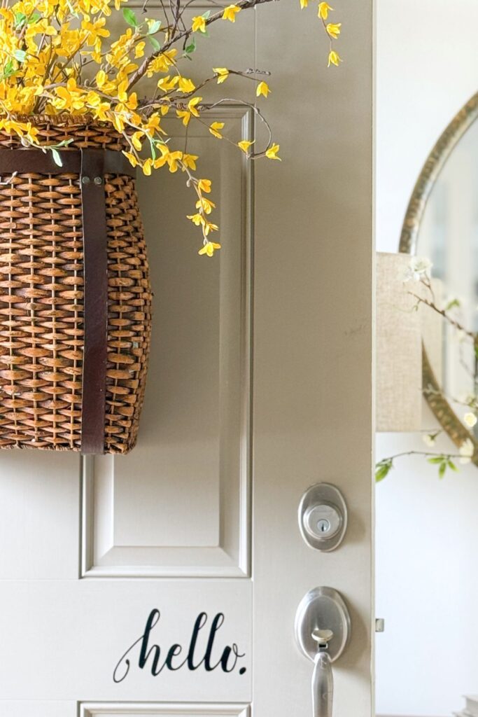 spring front door with woven basket filled with yellow flowering branches and hello door sign