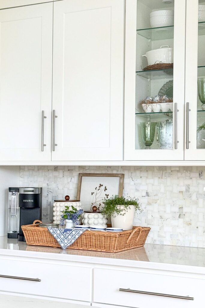 spring kitchen counter styled with a woven tray, greenery, and simple decorative accents
