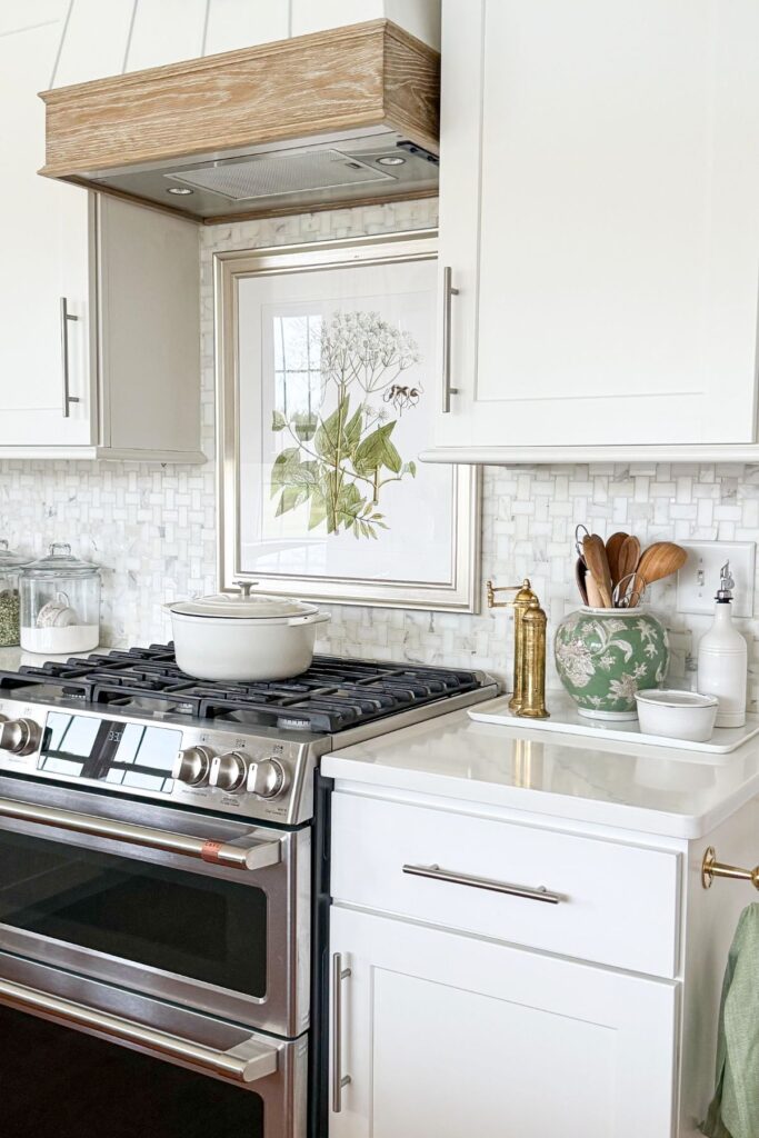 spring kitchen decorating with botanical artwork above the stove and simple green accents on the countertop