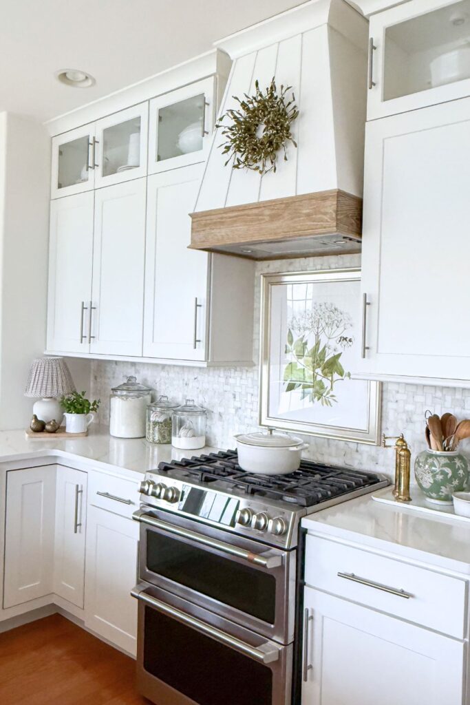bright spring kitchen with white cabinets, botanical artwork above the stove, and simple seasonal decor