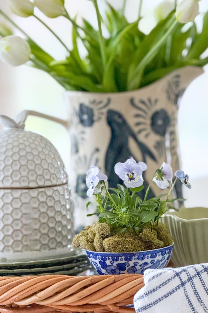 spring tray decor with small violet plant, white tulips in a patterned pitcher, and simple seasonal accents