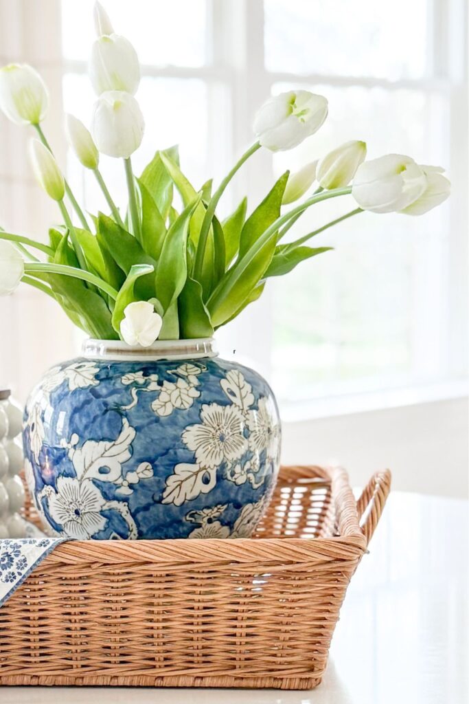 blue and white vase with white tulips styled in a wicker basket for simple home decor