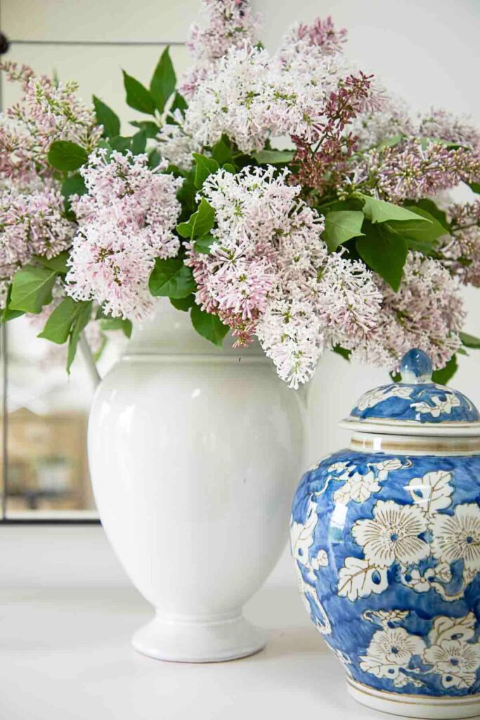blue and white ginger jar styled with white vase and soft pink flowers on a table