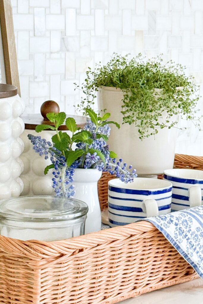 blue and white kitchen decor with striped mugs, greenery, and woven basket on counter