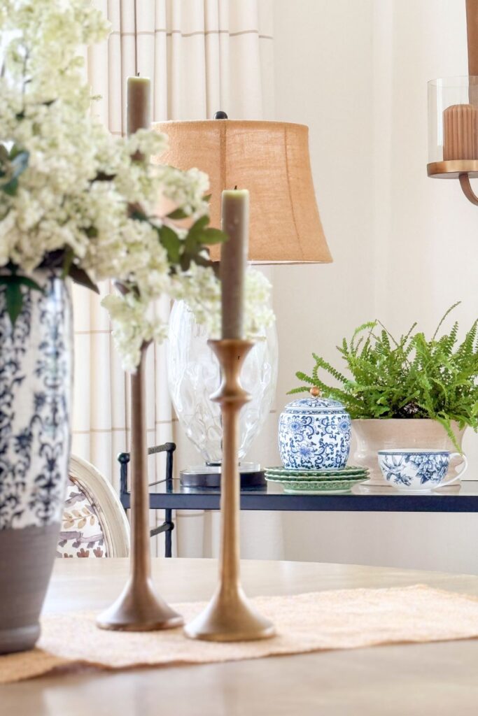 blue and white decor styled on a shelf with greenery, lamp, and neutral accents