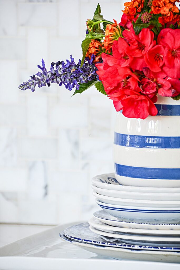 blue and white decorating ideas with striped crock and red flowers on stacked dishes