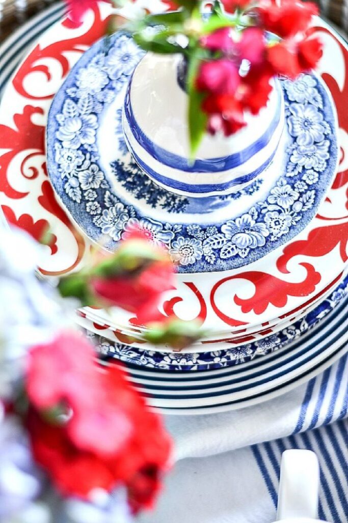 blue and white dishes layered with red patterned plate and flowers for seasonal decorating