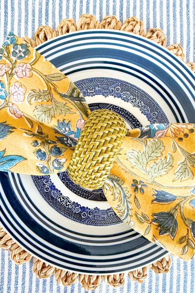 blue and white dishes layered with yellow napkin and woven textures on table