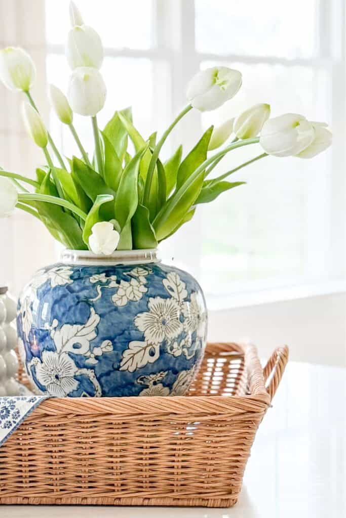 kitchen island styled with blue and white vase filled with tulips on a woven tray in a bright kitchen