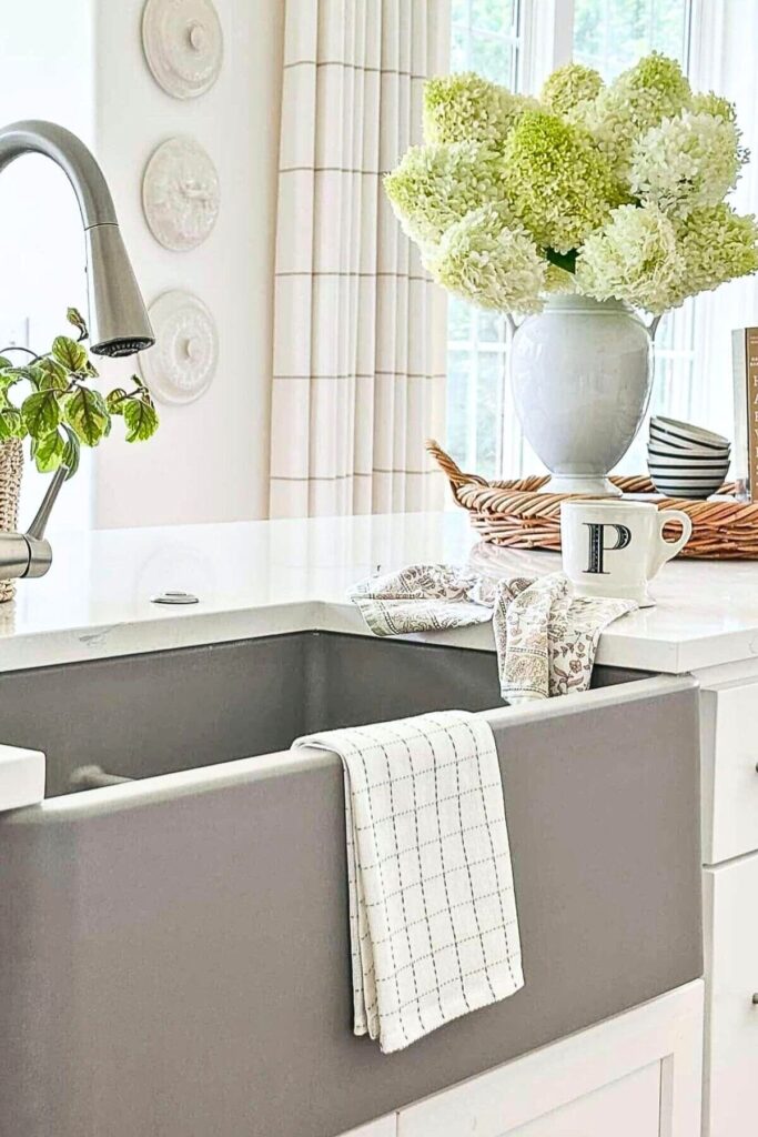 kitchen island styled with white hydrangeas in a vase on a tray with a mug and tea towel in a neutral kitchen