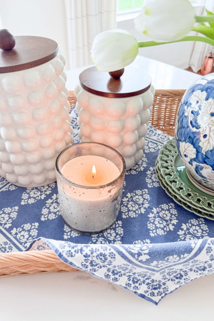 kitchen island styled with candle blue and white textiles and decorative containers on a woven tray