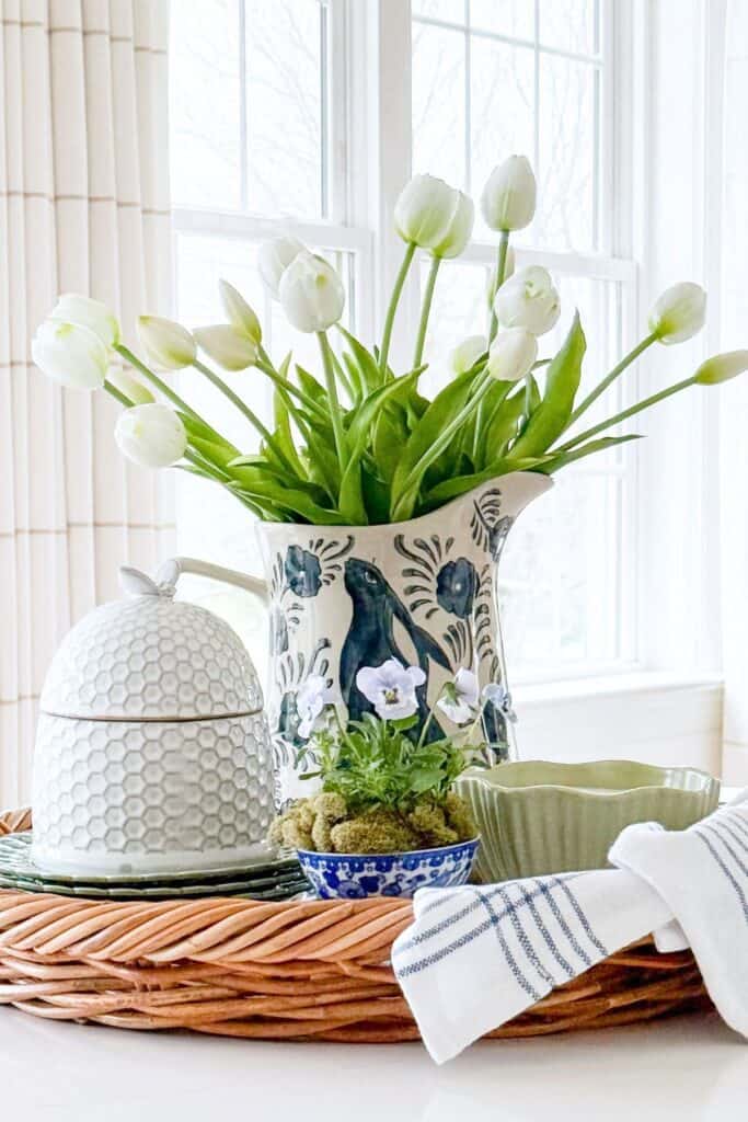 kitchen island styled with white tulips in a pitcher on a tray with blue and white decor and tea towel