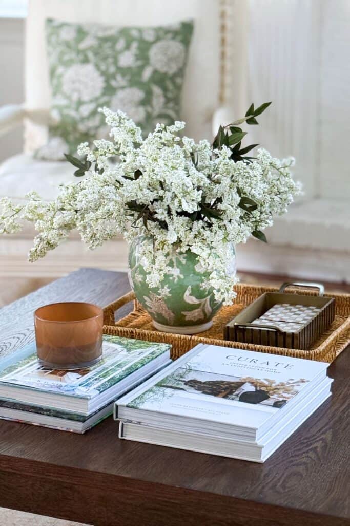 green and white chinoiserie planter filled with white fluffy blooms on a coffee table