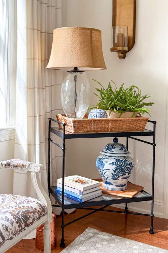 beautiful oil rubbed bronze bar cart with a basket, lamp, and fern on the shelf
