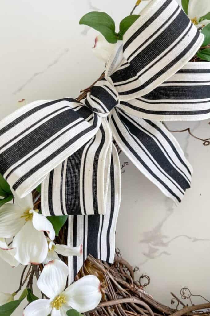 Close up of black and white striped ribbon bow on wreath with dogwood flowers for summer decor