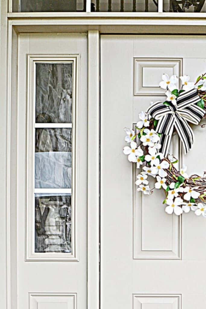 Dogwood wreath with black and white striped ribbon on a front door for summer decorating