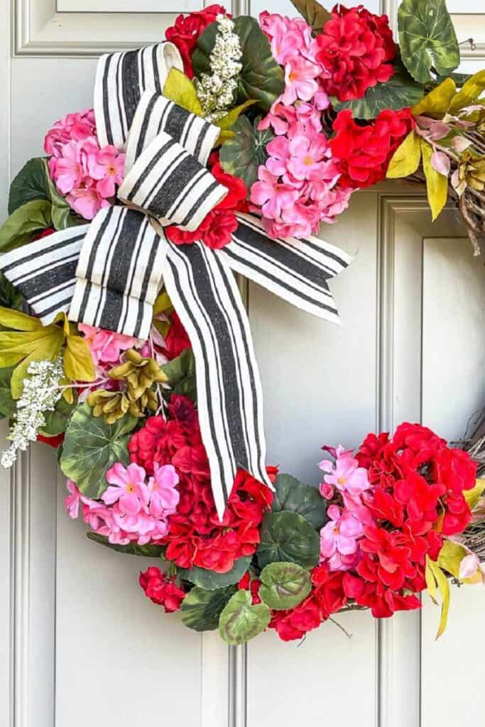 Summer geranium wreath with black and white ribbon on a front door