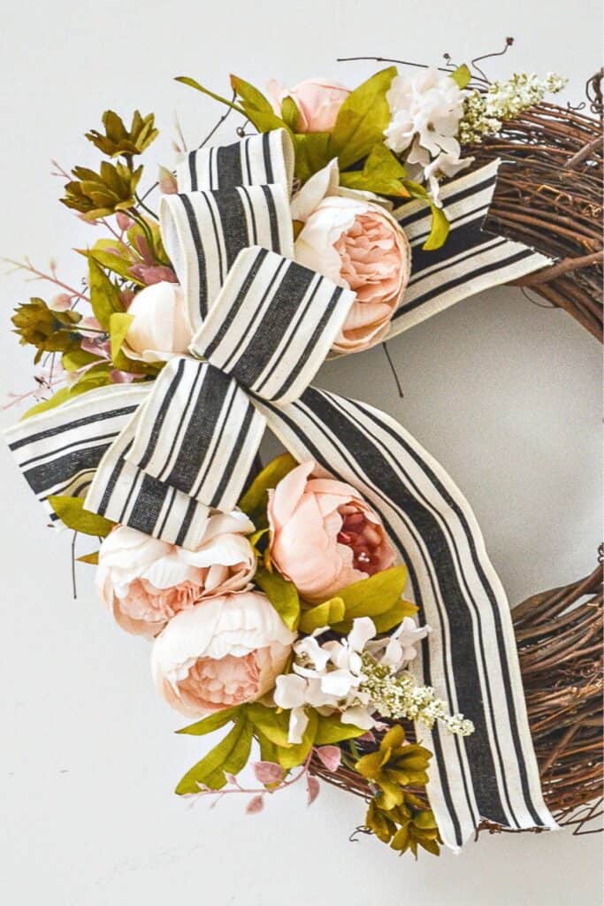 Close up of peony wreath with black and white striped ribbon for summer front door decor
