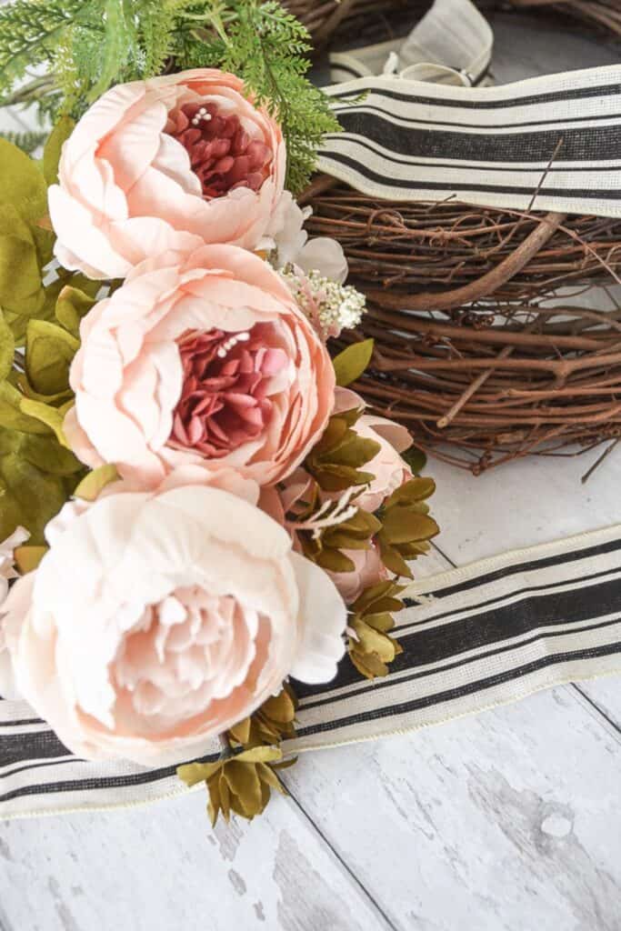 Peonies ribbon and grapevine wreath base used to create a summer front door wreath