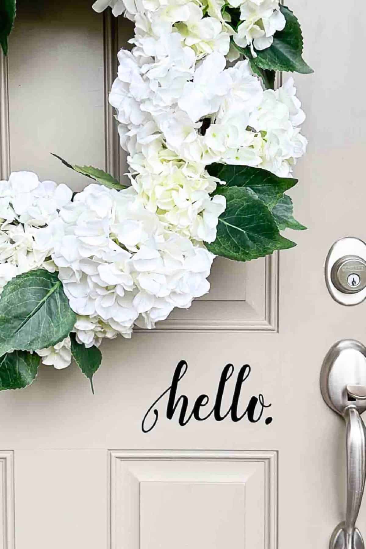 hello decal on a front door and a white hydrangea wreath.