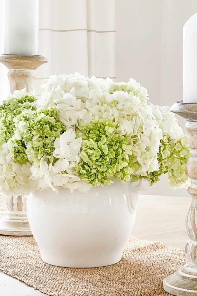 Elegant white and green hydrangea floral arrangement in a white ceramic vase.