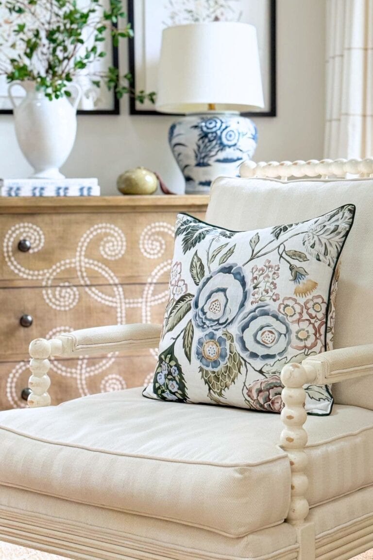 colorful pillow on a white spindle chair with a chest in the background