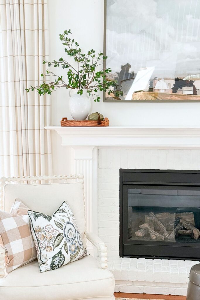 asymmetrical arrangement on a white mantel and a chair with pillows