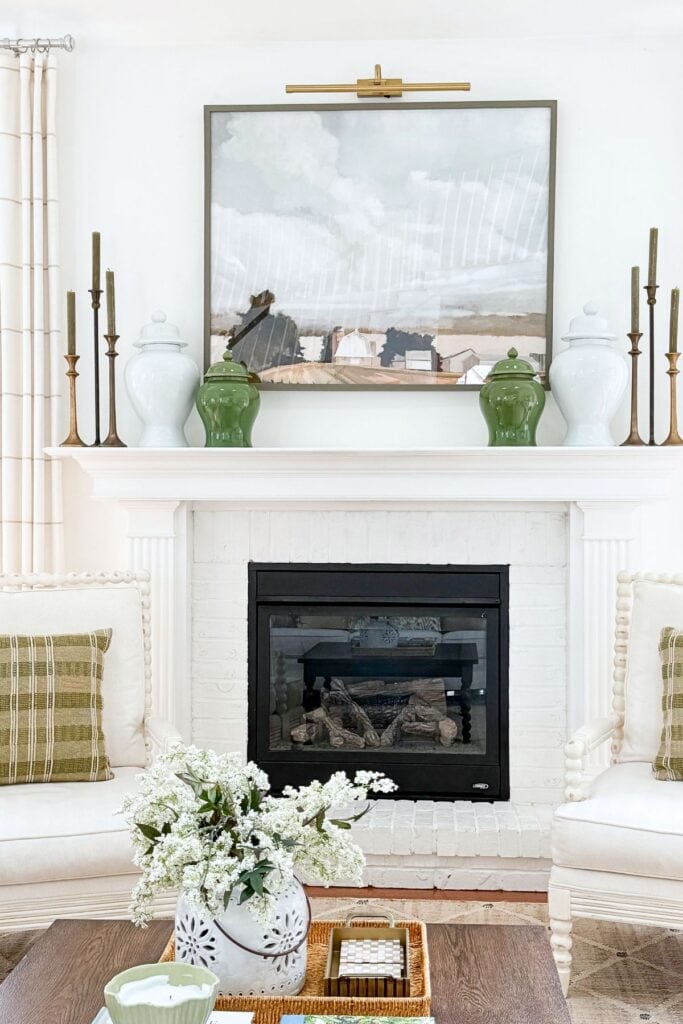 white and green ginger jars flanking a painting on a mantel