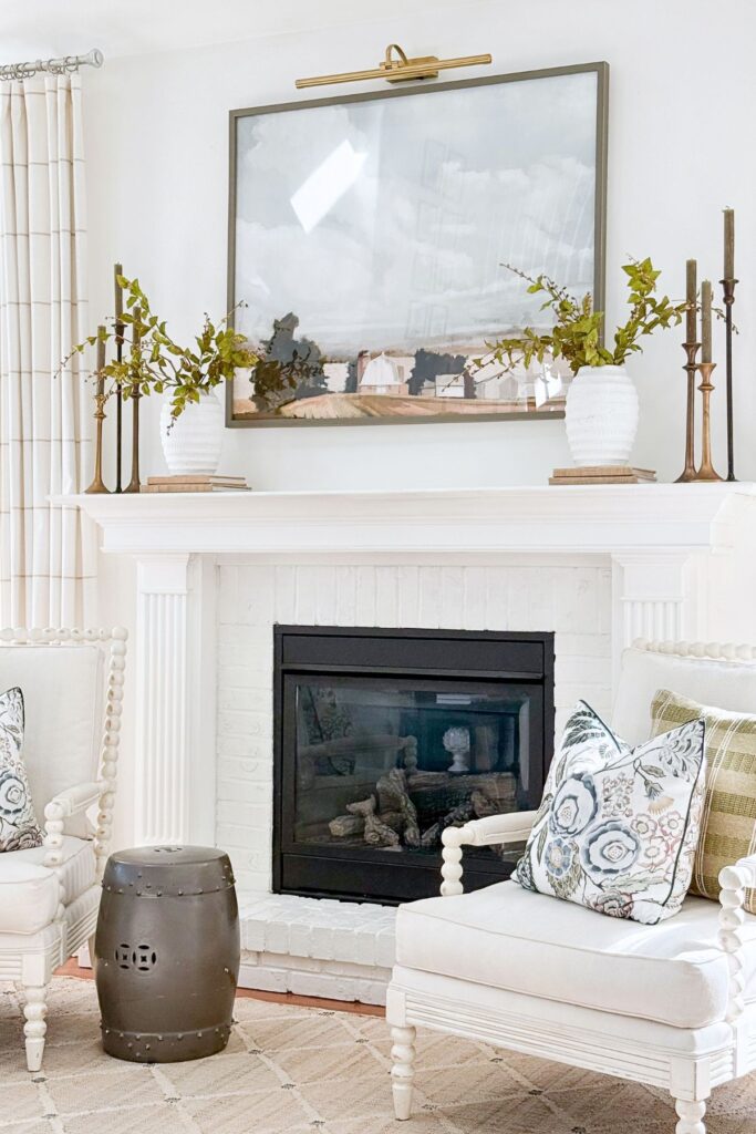 symmetrical decor on a white mantel above art