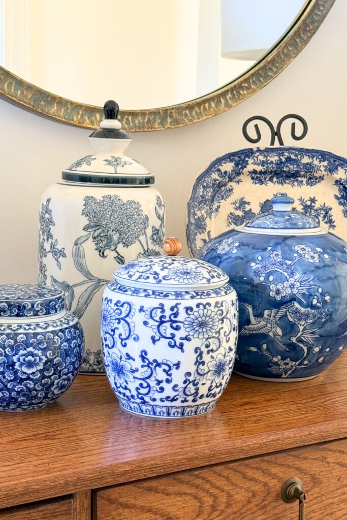 A grouping of blue and white ginger jars in varying sizes displayed on a wood dresser