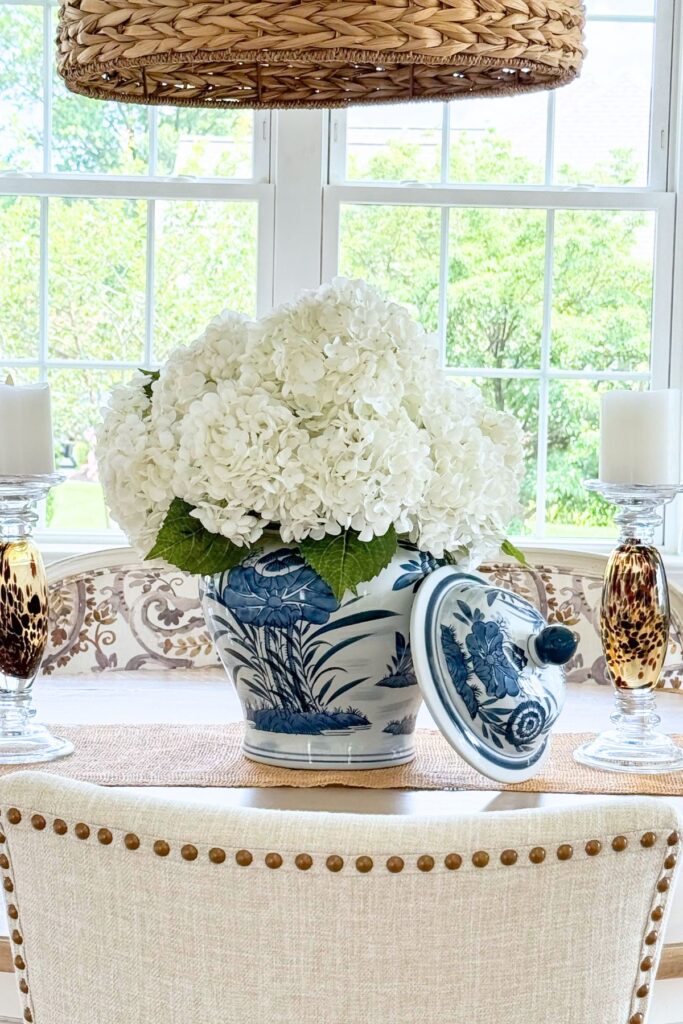 Blue and white ginger jar filled with faux white hydrangeas as a dining table centerpiece