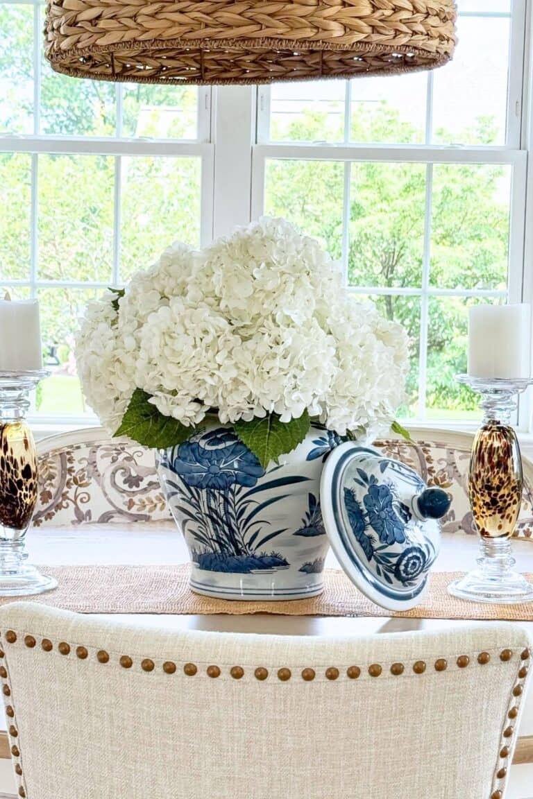 Blue and white ginger jar filled with faux white hydrangeas as a dining table centerpiece