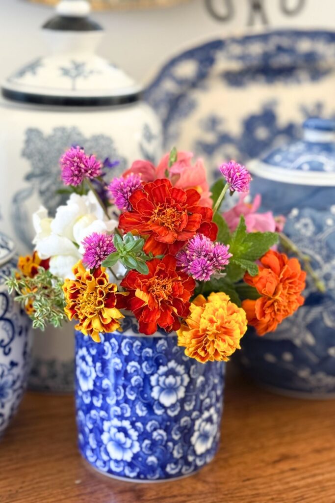 Small blue and white ginger jar filled with fresh marigolds and garden flowers
