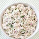 Overhead view of a full bowl of herby chicken salad with fresh dill, celery, and red onion