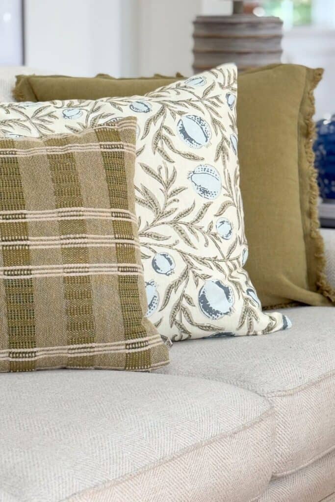 New summer pillows in olive plaid, botanical print, and solid green layered on a linen sofa for a midsummer decorating refresh