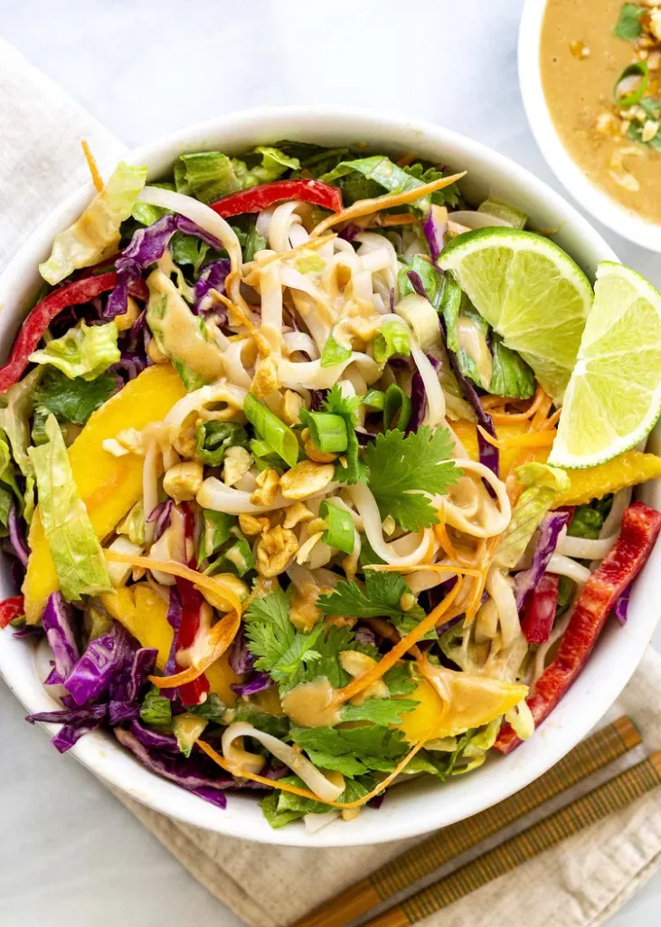Thai Salad in a white bowl with sliced limes