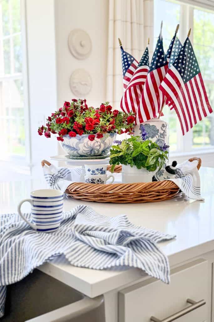 American flags and red flowers styled in a kitchen counter vignette before packing away patriotic decor for a midsummer refresh
