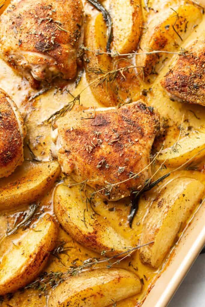 chicken and onions in juices on a ceramic sheet pan