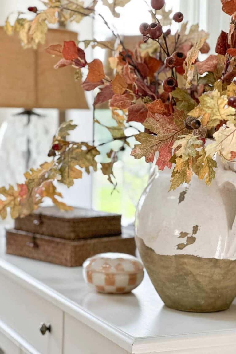 urn of fall branches and pods on a white buffet