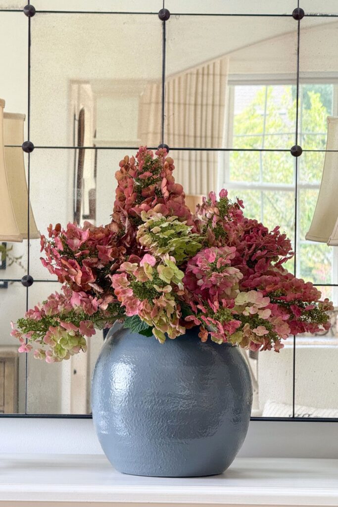 Dried pink and green hydrangeas in a matte blue vase, decorating with hydrangeas