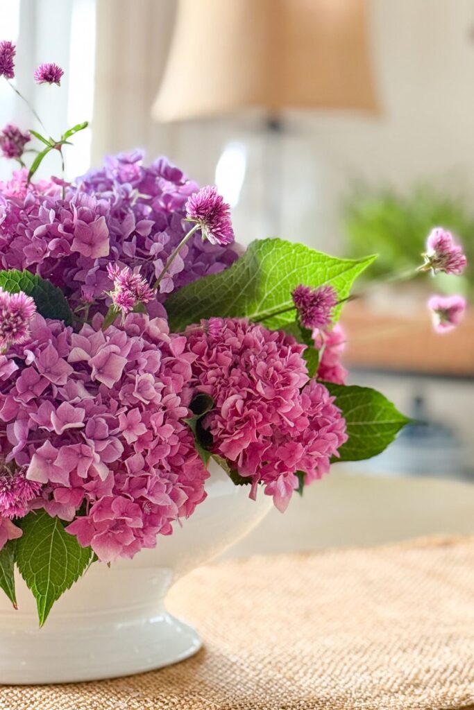 Fresh pink and purple hydrangeas with gomphrena in a white footed bowl