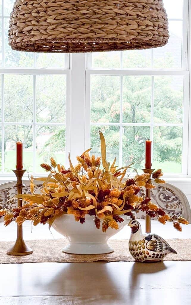 fall centerpiece on a dining room table with a ceramic partridge