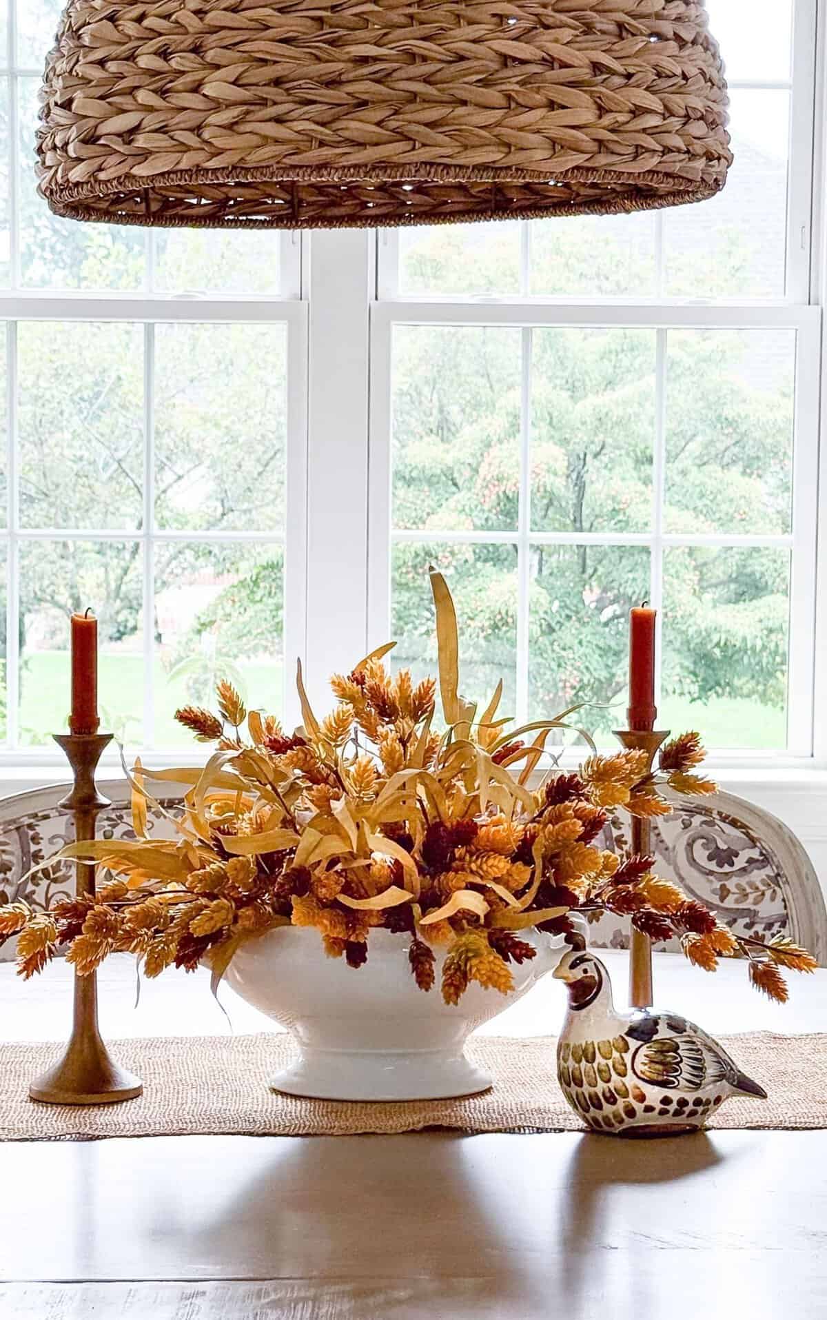 fall centerpiece on a dining room table with a ceramic partridge
