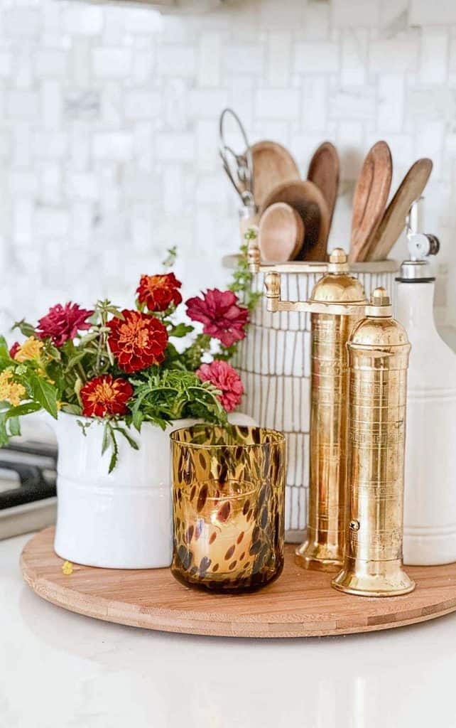 kitchen utinsels, brass salt and pepper mill, a candle and freshly picked flowers