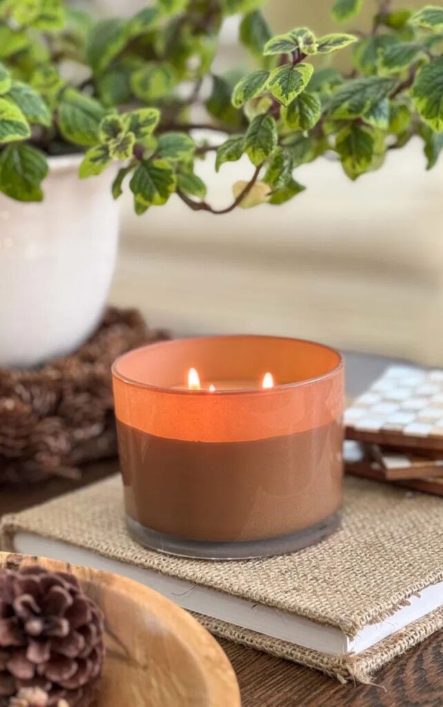 a pumpkin candle in a fall vignette on a coffee table