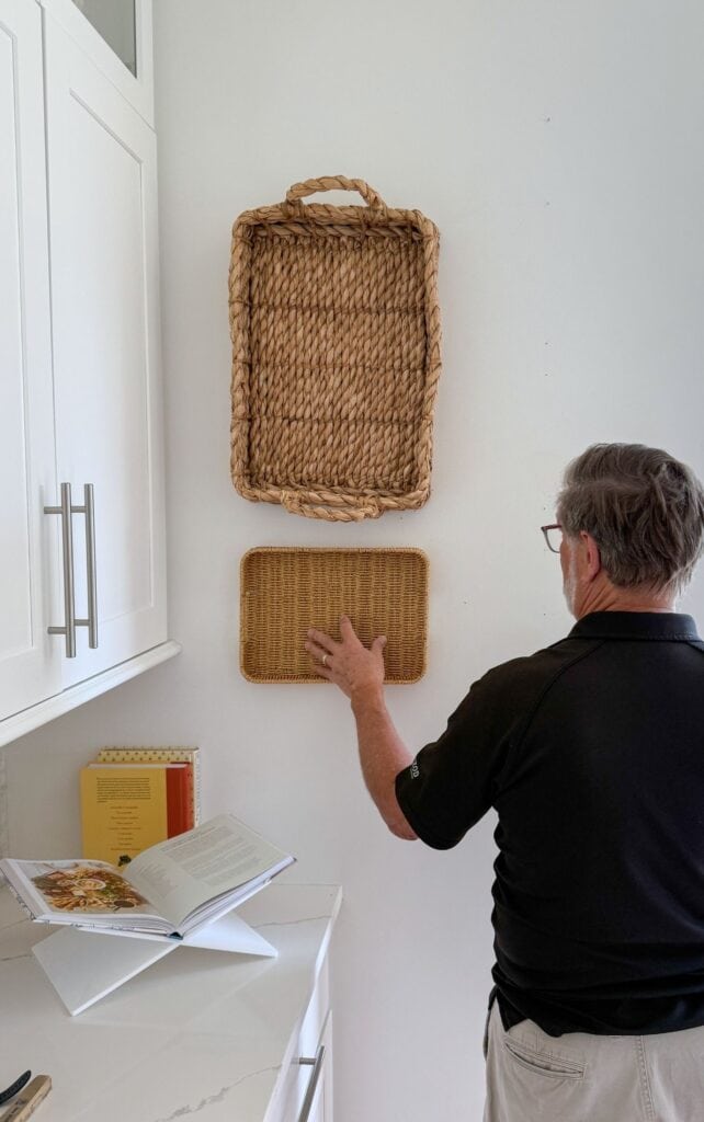 Man hanging a woven basket on the wall before adding plates