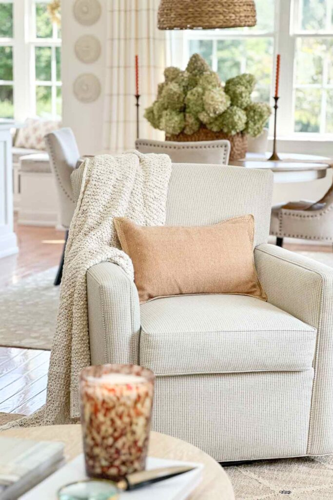 a chair with a neutral pillow and a throw. Drying hydrangeas in a basket on a dining room table