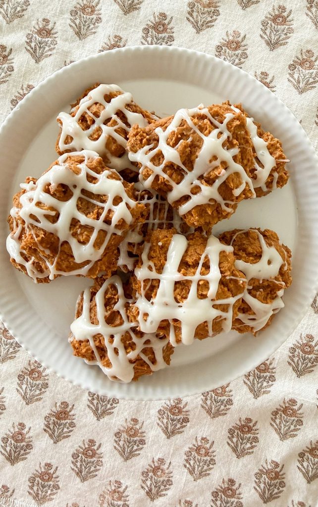 Overhead view of pumpkin spice cookies with cream cheese drizzle on a white ruffled plate